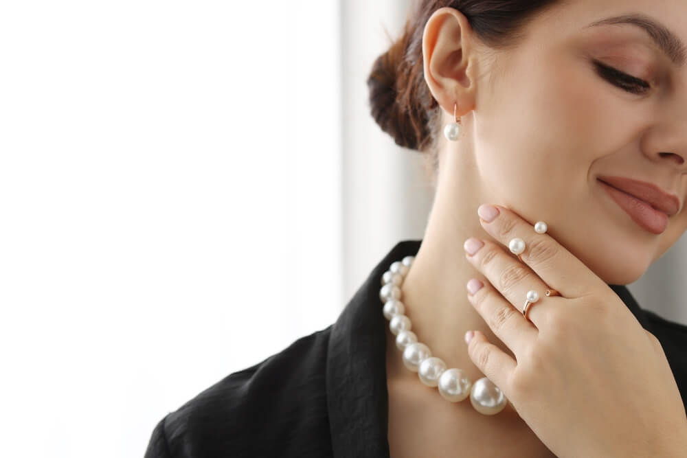 A young woman showcasing elegant pearl jewelry indoors — a perfect reminder of why high-value item insurance is essential.