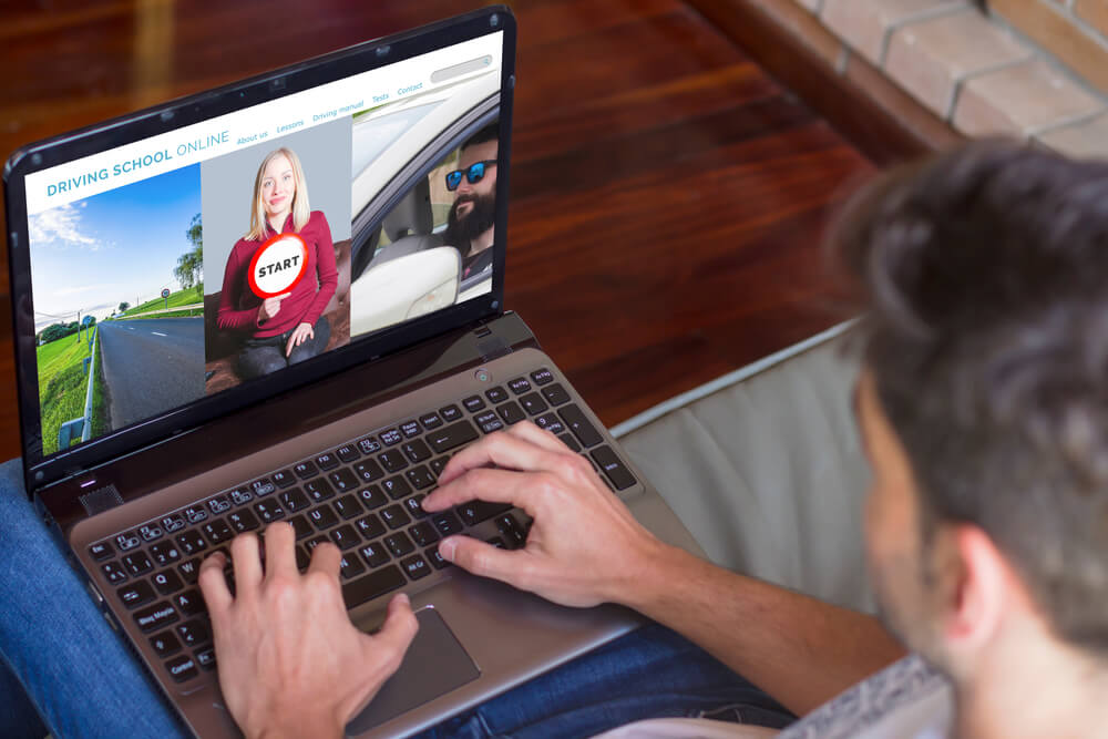 Male sits on couch at home and takes an online driver's course, driver's safety course and lowering insurance rates.