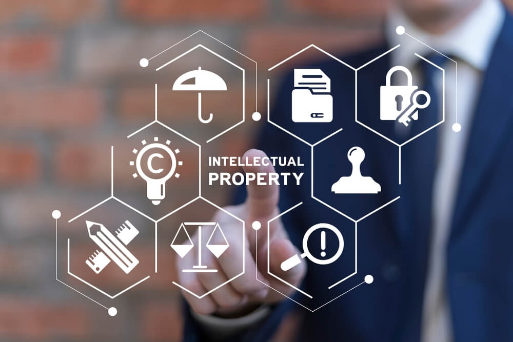 Business man working on virtual touch screen presses inscription: INTELLECTUAL PROPERTY. How business insurance can help you protect intellectual property and trade secrets.