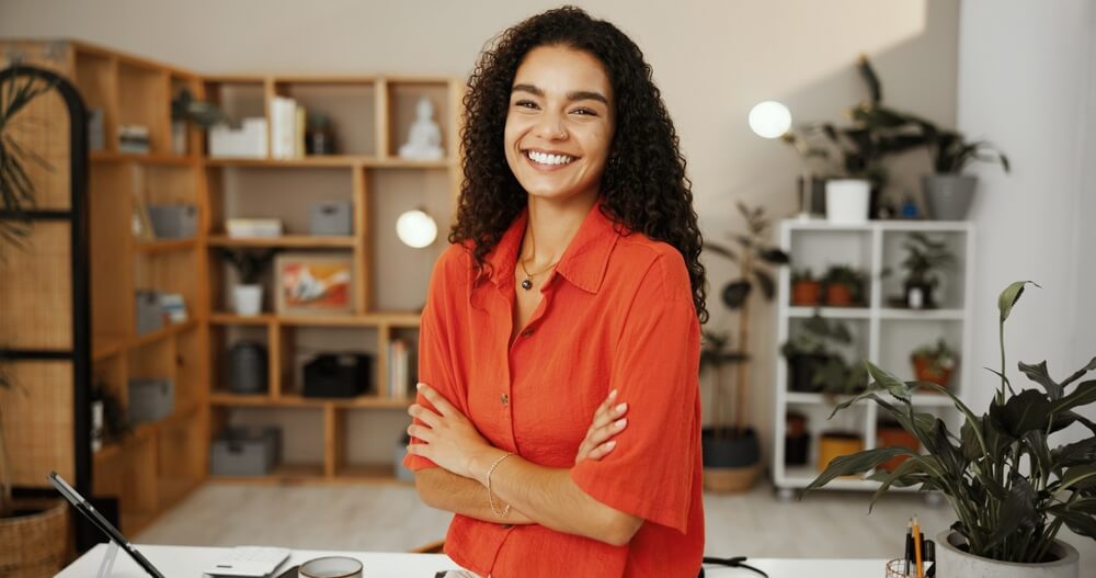 Small business, portrait and woman with arms crossed, confident and smile for sales in flower and gift shop, happy with small business insurance coverage.