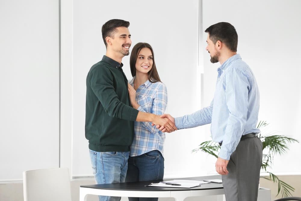 Insurance agent shaking hands with couple who just rented an apartment and purchased renters insurance.