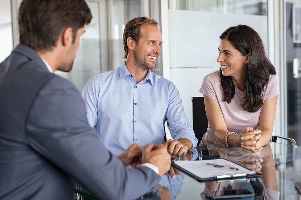 Mature smiling couple meeting insurance agent to purchase commercial property insurance and other business insurance for their medium-sized company.