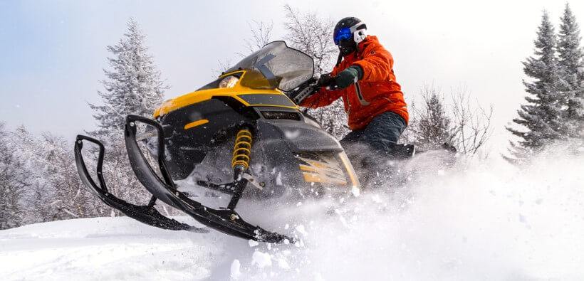 man in mountain with snowmobile