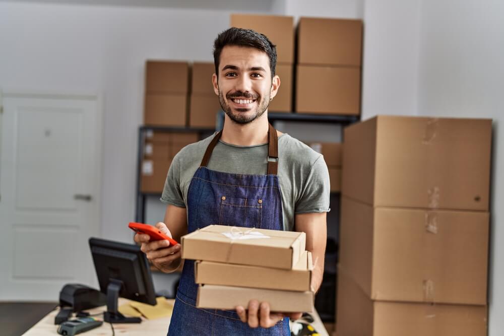 Man holding three cardboard boxes and a cell phone