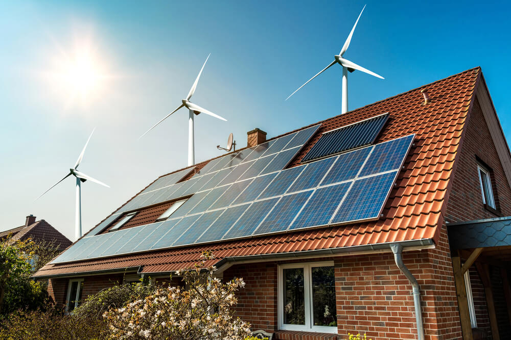 A green home with solar panels and windmills to generate electricity.