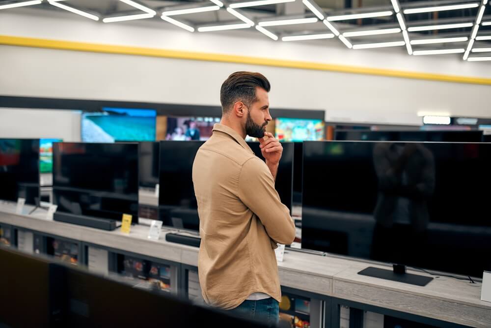 Man looking at TV to buy.