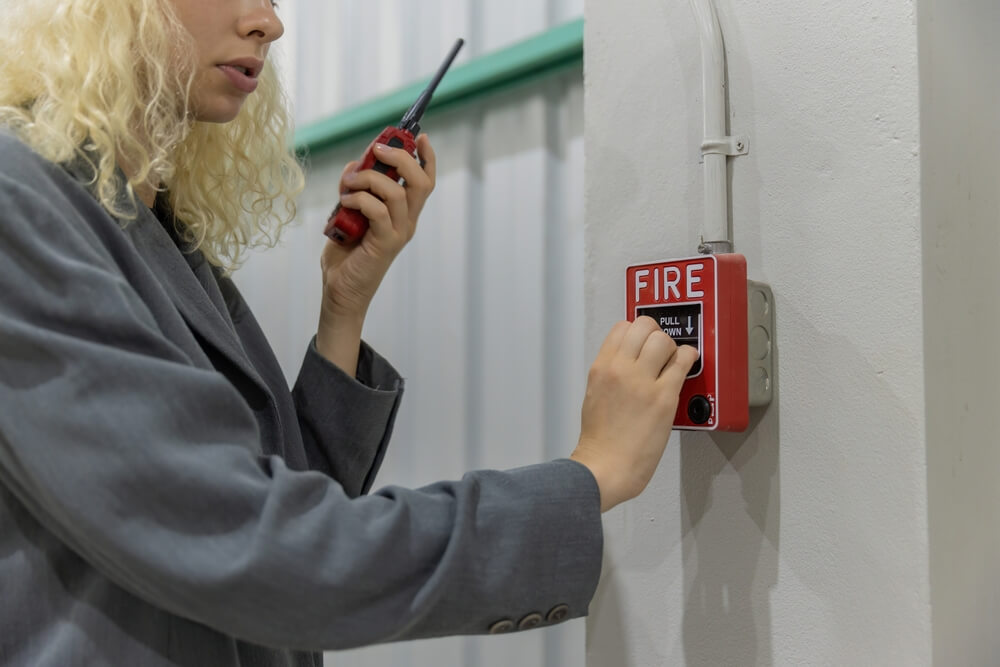 Woman speaks into walkie-talkie and pulls down the fire alarm, best business insurance.