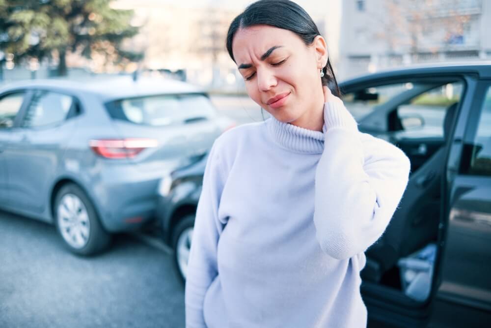 Young woman rubs her neck after a car accident - best car insurance.