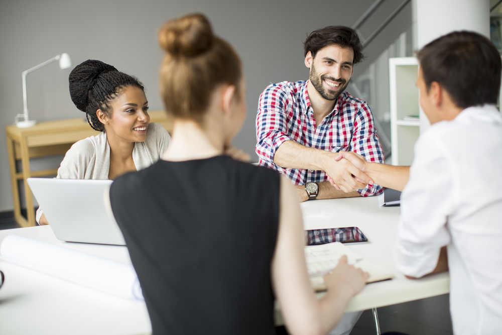 New employee smiling shaking hands with boss