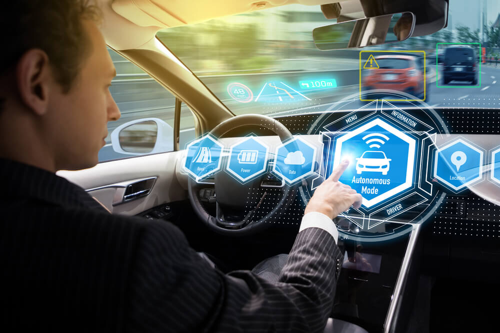 A man sitting inside a modern vehicle in front of the steering wheel, exploring autonomous driving options.