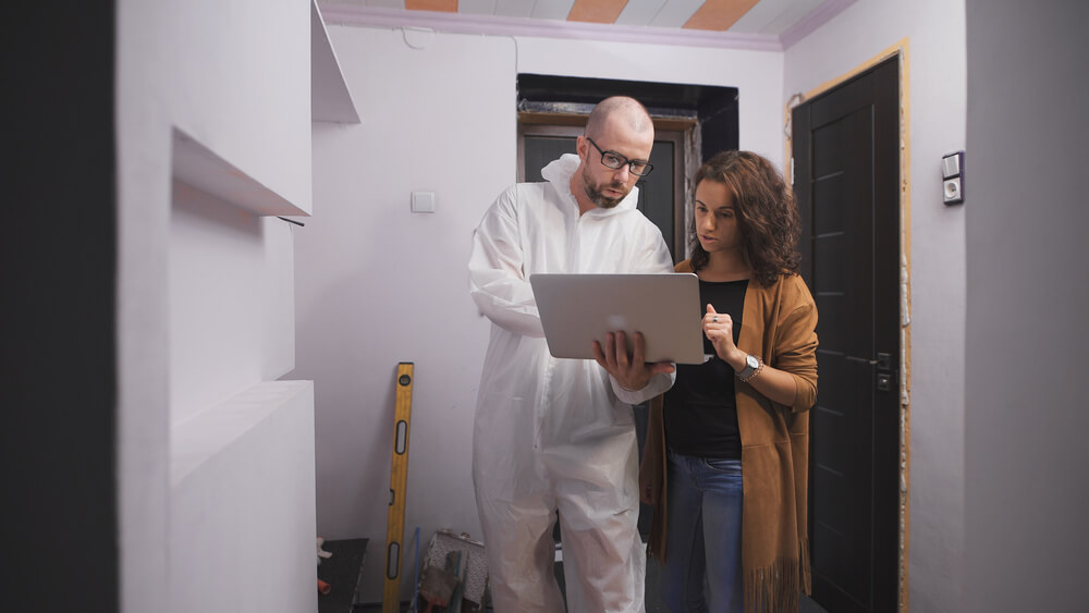 Repairman in protective clothing shows a homeowner what the repairs will cost - best home insurance.