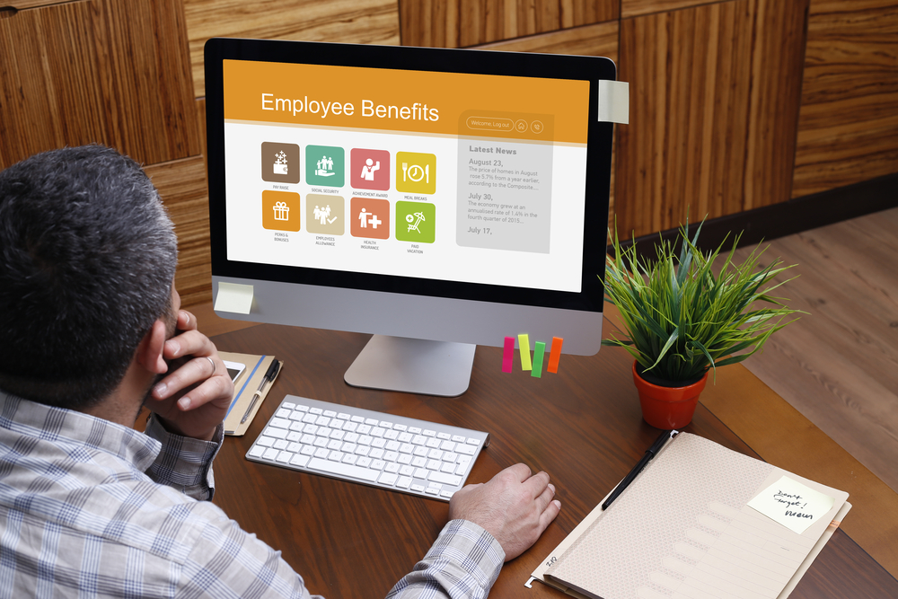 Man reads about employee benefits on laptop