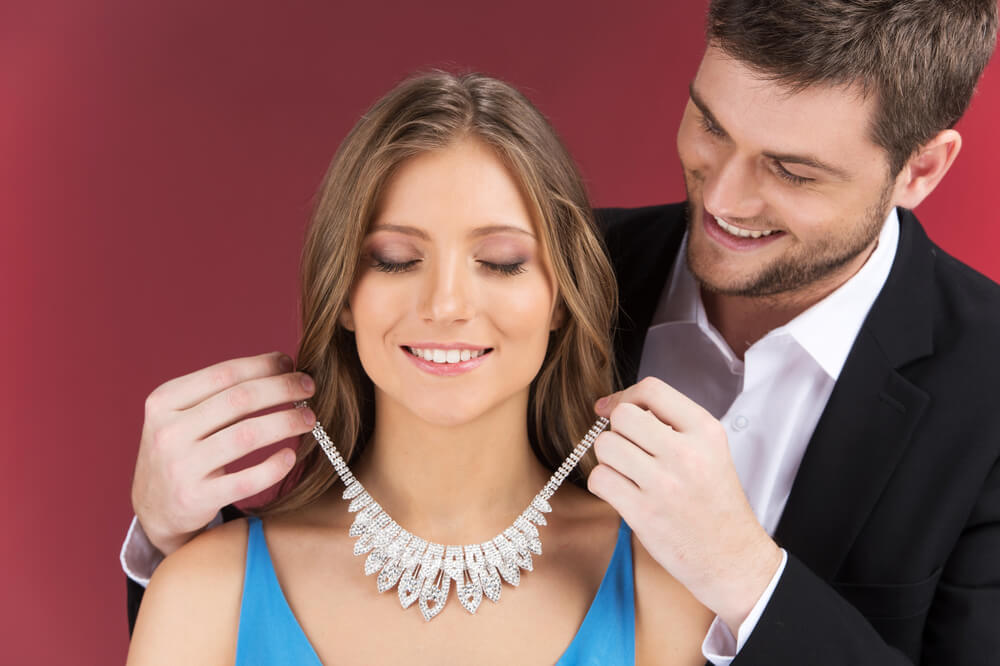 Man puts expensive diamond necklace on woman.